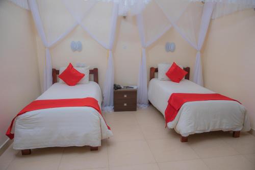 two beds in a room with red pillows at Miika Eco Resort Hotel in Hoima
