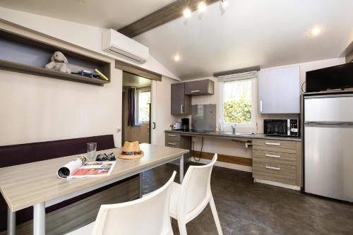 a kitchen with a wooden table and white appliances at Camping Lou Pignada ***** in Messanges
