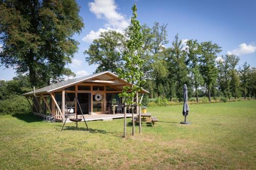 a small cabin in a field with an umbrella at Landrijk De Reesprong boerderij in Haaksbergen