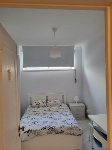 Dormitorio pequeño con cama y ventana en K House en Odivelas