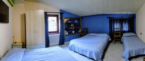 2 camas en un dormitorio con paredes azules en Bed and Breakfast La Spina en Poggiridenti