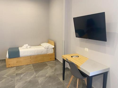 a small room with a bed and a desk and a television at Be Italian Flat Sanfelice in Naples
