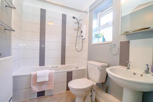 La salle de bains blanche est pourvue de toilettes et d'un lavabo. dans l'établissement Country View Cottage, à Halvergate