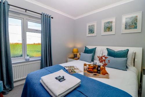 a bedroom with a bed with a blue blanket and a window at Country View Cottage in Halvergate