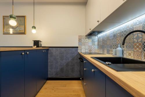 ポズナンにあるHomewell Apartments Czartoria- free parkingの青いキャビネットとシンクのあるキッチン