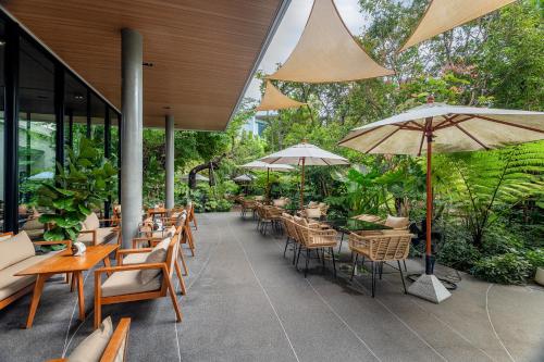 an outdoor patio with tables and chairs and umbrellas at Timberton Resort Khaoyai in Ban Tha Maprang