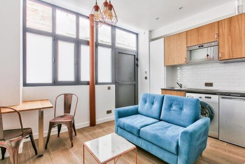 un salon avec un canapé bleu et une table dans l'établissement Suite Montorgueil, à Paris