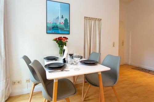 uma mesa de jantar branca com cadeiras e um quadro em Das City-Appartment Zentrum West em Leipzig