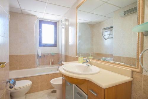 a bathroom with a sink and a toilet and a mirror at Apartamento Coral Beach - PlusHolidays in Calpe