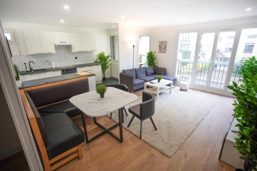 a kitchen and a living room with a table at Keyless Appartement Moderne et Spacieux 90 m2 Parking, Métro 14 Paris - Orly in Chevilly-Larue