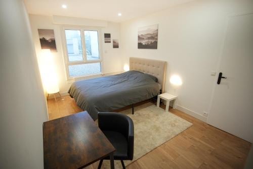 a bedroom with a bed and a table and a chair at Keyless Appartement Moderne et Spacieux 90 m2 Parking, Métro 14 Paris - Orly in Chevilly-Larue