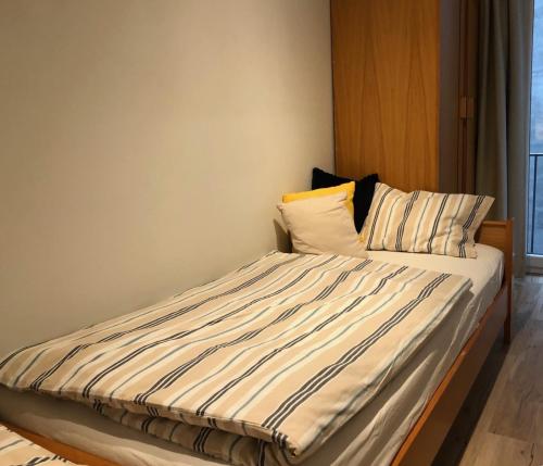 a bed with striped sheets and pillows in a room at appartement DE WATERLIJN in Knokke-Heist