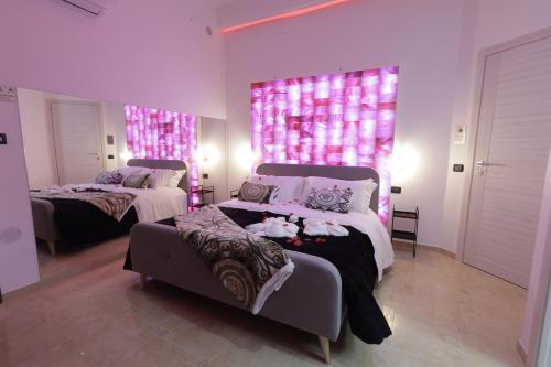 2 camas en una habitación con luces rosas en la pared en B&B GRECALE Suite & Spa, en Rende