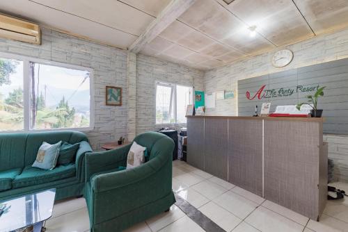 a living room with two green chairs and a counter at Urbanview Resort Anty Cisarua Tugu Puncak by RedDoorz in Sampal 2