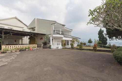 a large white house with a large driveway at Urbanview Resort Anty Cisarua Tugu Puncak by RedDoorz in Sampal 2