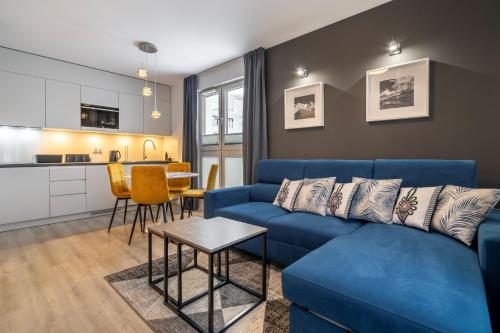 a living room with a blue couch and a kitchen at RentPlanet - Apartamenty Zakopiańskie in Zakopane