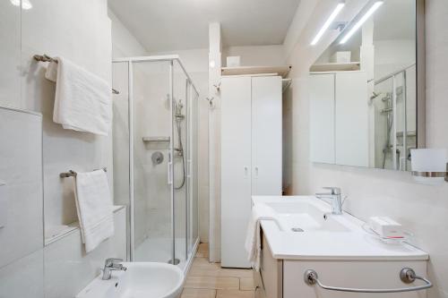 a white bathroom with a shower and a sink at La Tana Dell'Ermellino 3 Ski In Ski Out - Happy Rentals in Sestriere