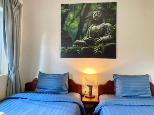 a room with two beds and a painting of a buddha at Lotus Haven Villa in Siem Reap