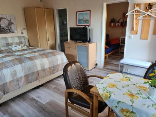 a bedroom with a bed and a table and a television at Ferienhaus Bungalow nahe Kurpark Döse in Cuxhaven
