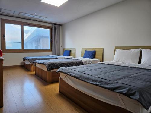 a room with three beds and a window at Samda Hostel in Jeju