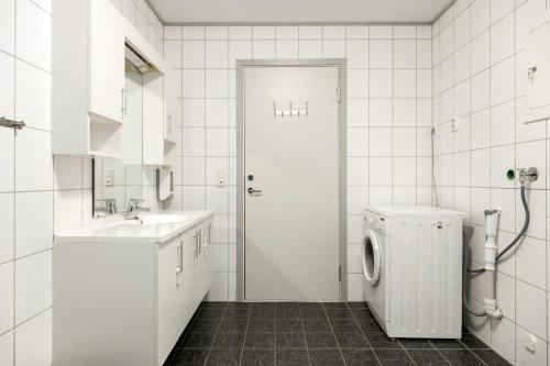 a white bathroom with a sink and a washing machine at Flåm Station Apartments in Flåm