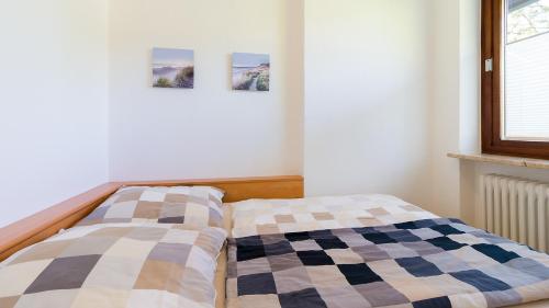 クックスハーフェンにあるUrlaub mit Blick auf die Duhner Heideの壁に2枚の写真が飾られたベッドルームのベッド2台