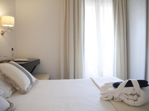 a white bed with a towel on it with a window at California Park Hotel in Forte dei Marmi