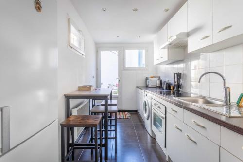 La cuisine est équipée de placards blancs, d'un évier et d'un comptoir. dans l'établissement Cozy 1 bedroom apartment in La Plaine district, à Marseille