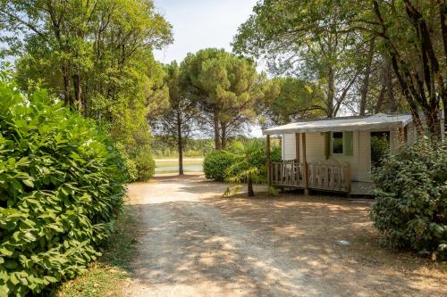 uma pequena cabana branca com um alpendre numa floresta em Camping le Lac de Thoux em Saint-Cricq