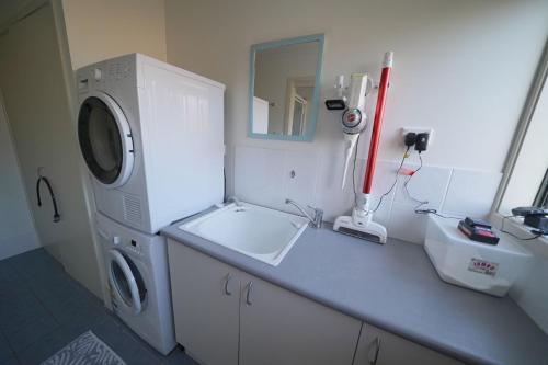 a bathroom with a washing machine and a sink at Quay Largo in Lake Tabourie