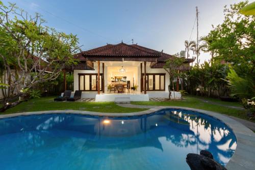 a swimming pool in front of a villa at Deby Villa Seminyak in Seminyak