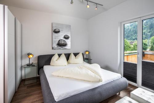 a bedroom with a bed with white sheets and a window at Apparthaus & Chalets Hofer in Zell am Ziller
