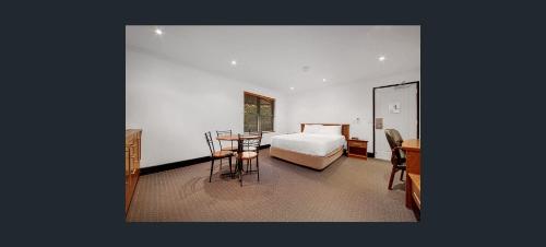 a bedroom with a bed and a table and a desk at Gladstone Capricorn Apartments in Gladstone