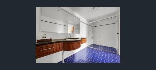 baño con lavabo y suelo de baldosa azul en Gladstone Capricorn Apartments, en Gladstone