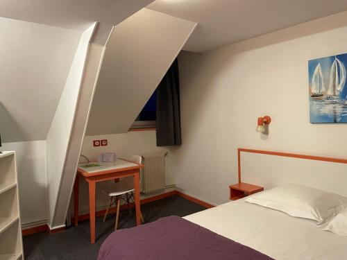 a small bedroom with a bed and a desk at Hôtel de la Plage in Fécamp