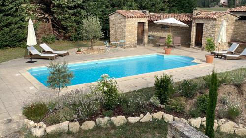 a swimming pool in a yard with chairs and an umbrella at Le Mas de Caroline in Gargas