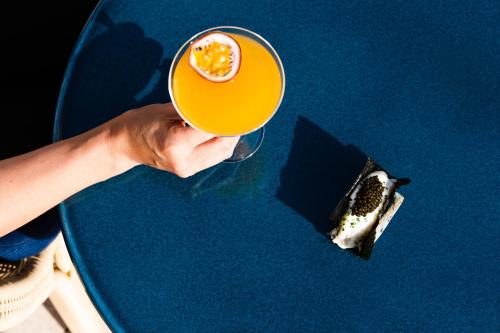 a person holding a glass of orange juice and a piece of food at The Standard, Ibiza in Ibiza Town