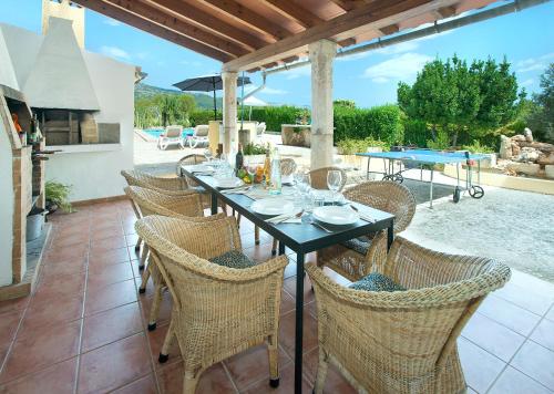 un patio con mesa de comedor y sillas y chimenea en Owl Booking Villa Alqueria Alt - Fantastic Mountain Views, en Campanet