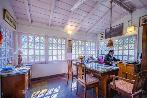 a man sitting at a desk with a computer in a room at Neemrana's - Ramgarh Bungalows in Rāmgarh