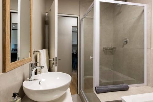a bathroom with a sink and a glass shower at Nivica 56 Luxury Apartment Langebaan in Langebaan