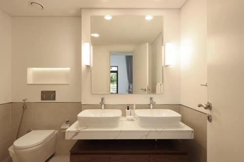 a bathroom with two sinks and a toilet and a mirror at Livbnb - 2BR close to Souk Mall and Burj Al Arab in Dubai