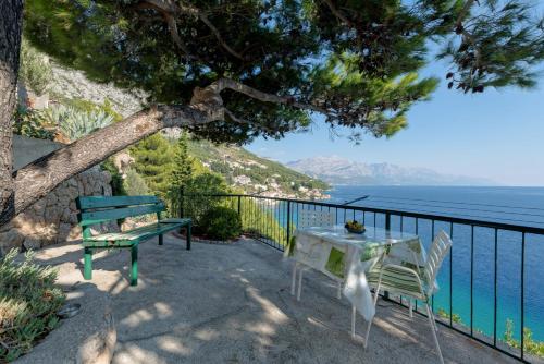 a table and a bench sitting next to the ocean at Apartments TOM in Mimice