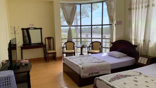 a bedroom with two beds and a table and a window at Hung Vuong Hotel in Ben Tre