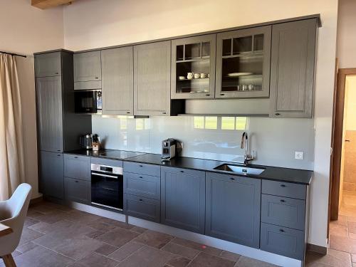 uma cozinha com armários cinzentos e bancadas pretas em Landhaus Huber em Fügen