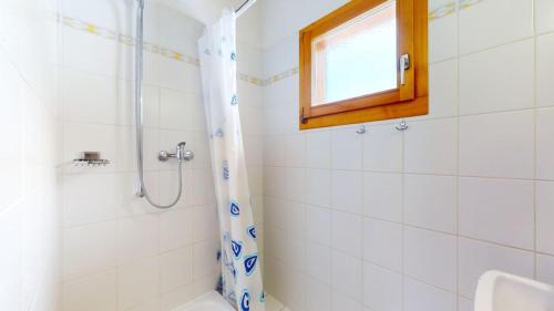 a white bathroom with a shower and a window at Fontannets COSY & MOUNTAIN chalets in Veysonnaz