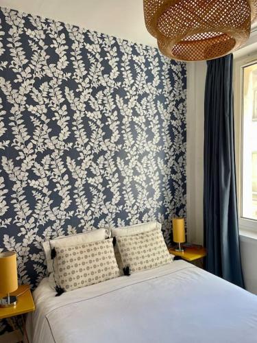 a bedroom with a bed with a blue and white wallpaper at Appartement à côté de la plage avec balcon filant in Trouville-sur-Mer