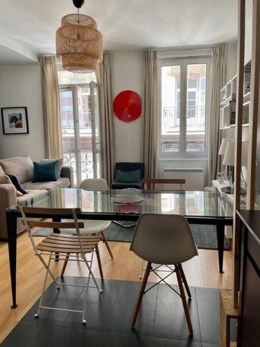 un salon avec une table en verre et des chaises dans l'établissement Appartement à côté de la plage avec balcon filant, à Trouville-sur-Mer