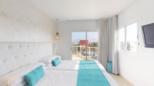 Dormitorio blanco con cama y ventana grande en Cala Millor Garden Hotel - Adults Only, en Cala Millor