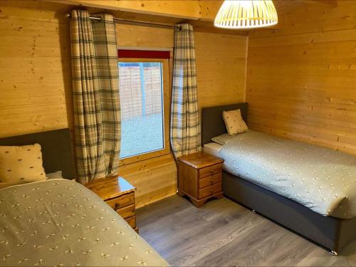 a bedroom with two beds in a log cabin at Inviting 2-Bedroom Cabin in Ashton Under Hill in Evesham