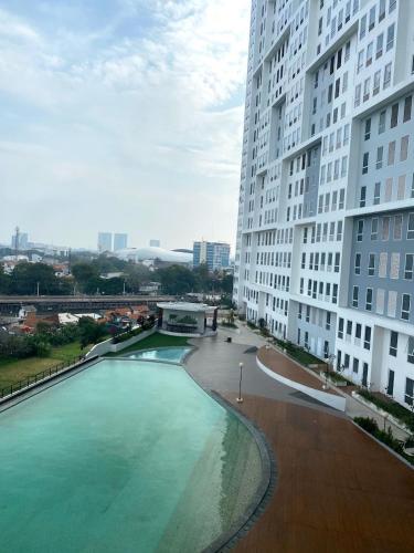 a large pool of water next to a tall building at Apartemen Patraland Urbano By Public Room in Bulanbulan